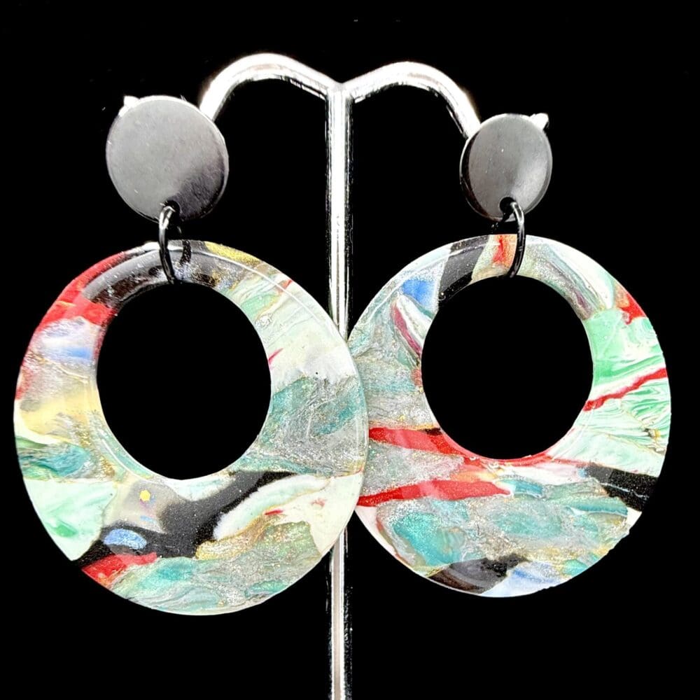 Polymer clay statement hoop earrings with bold abstract swirls in red, black, teal, white, and gold; lightweight design with matte, flat, black stud tops.
