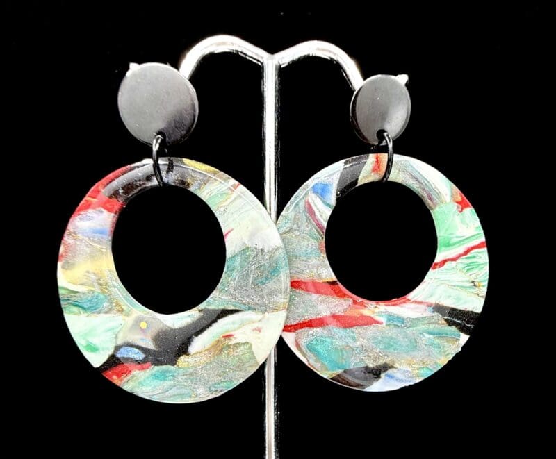 Polymer clay statement hoop earrings with bold abstract swirls in red, black, teal, white, and gold; lightweight design with matte, flat, black stud tops.